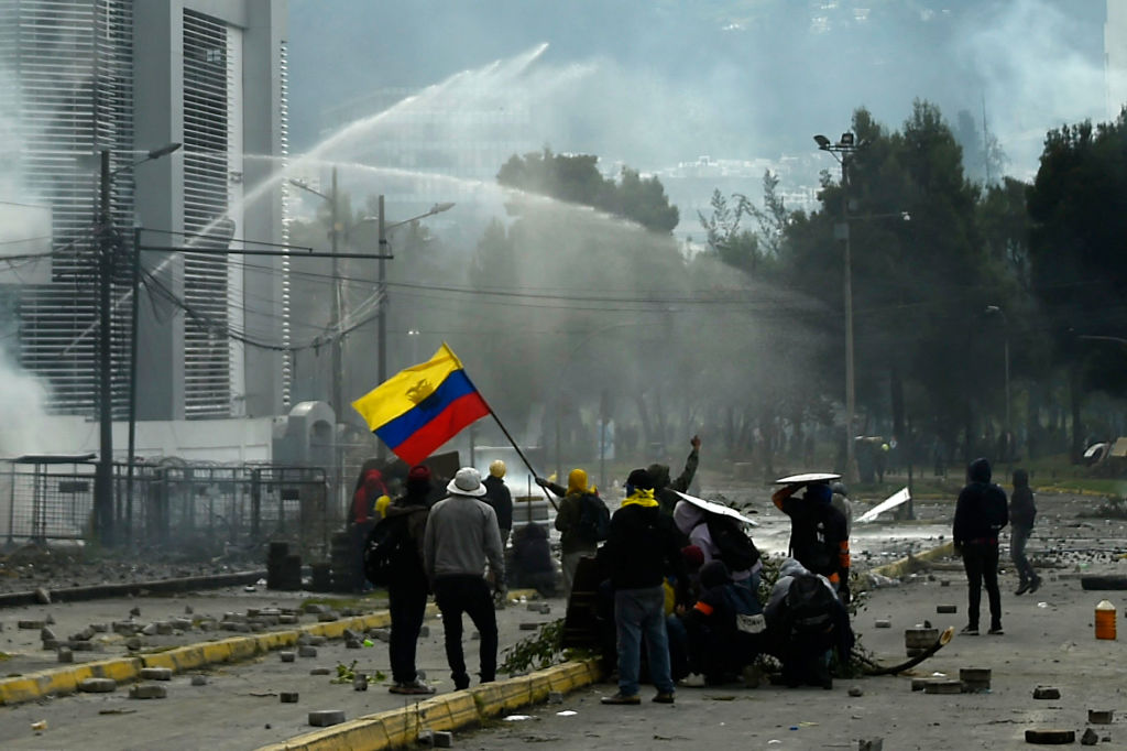 TOPSHOT â Demonstrators wave an Ecuadorean flag during clashes with riot police in the surroundings of El Arbolito park in Quito on June 24, 2022, in the framework of indigenous-led protests against the government. . (Photo by Rodrigo BUENDIA / AFP) (Photo by RODRIGO BUENDIA/AFP via Getty Images)