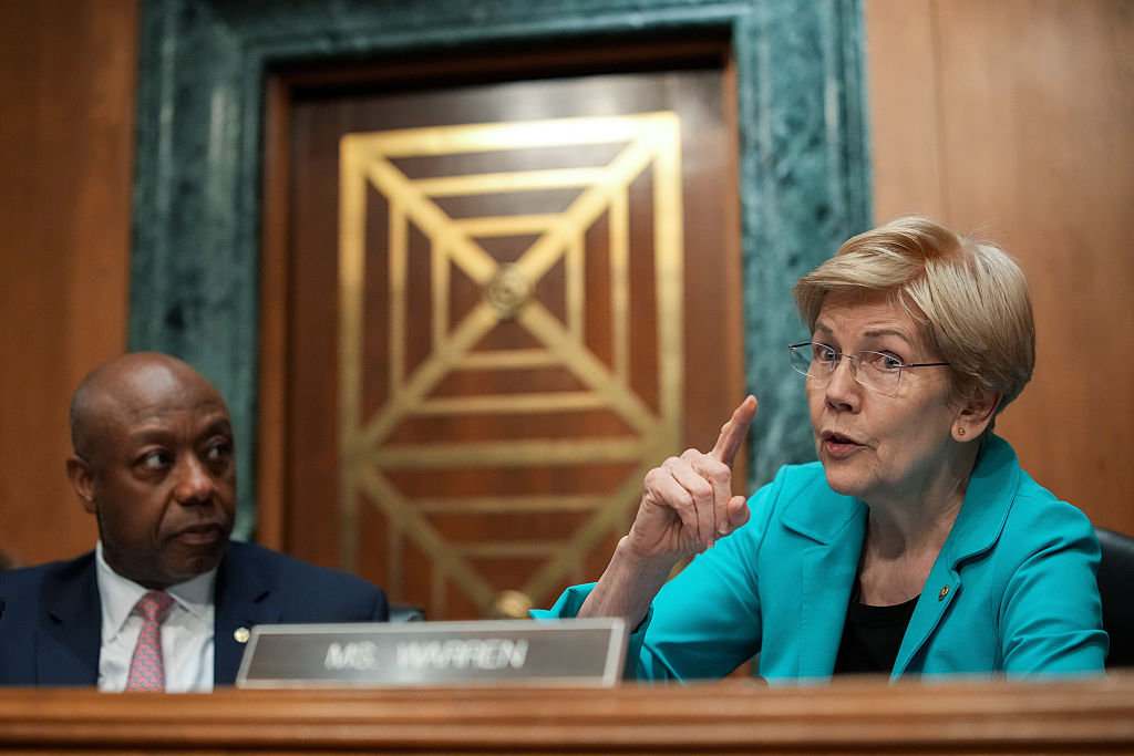 WASHINGTON, DC – APRIL 21: (L-R) Committee Chairman Sen. Tim Scott (R-SC) looks on as ranking member Sen. Elizabeth Warren (D-MA) speaks during a Senate Committee on Banking, Housing, and Urban Affairs confirmation hearing for Kevin Warsh, U.S. President Donald Trump’s nominee for Chair of the Federal Reserve, in the Dirksen Senate Office Building on April 21, 2026 in Washington, DC. President Trump nominated Warsh, a former member of the Federal Reserve Board of Governors, to replace Jerome Powell amid bipartisan concerns over the Justice Department’s criminal investigation into the central bank’s current leader. (Photo by Andrew Harnik/Getty Images)